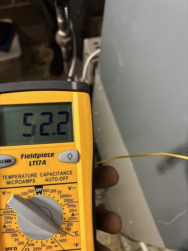 Completed A/C only installation with final system commissioning and verification. System electrical parameters were measured and confirmed within manufacturer specifications, with temperature readings of 52.2°F and 66.4°F recorded using calibrated test equipment to verify proper refrigerant charge and system performance.