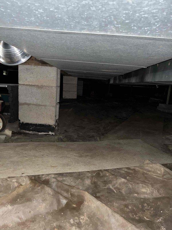 Completed comprehensive evaluation of existing HVAC air handler unit located in crawl space for equipment replacement estimate. Assessed current system configuration including air handler positioned on floor joists, refrigerant line routing, electrical connections via orange conduit, and flexible ductwork installation. Documented crawl space access conditions, structural support system with concrete block pillars, moisture presence on concrete flooring, and clearance limitations for equipment replacement considerations. Photographed existing unit specifications, refrigerant line insulation condition, and surrounding installation environment to provide customer with multiple replacement options and system upgrade recommendations.