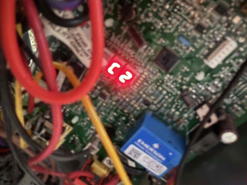 Responded to no cooling complaint following recent rain storm. Upon inspection, found outdoor unit had experienced electrical component failure due to water intrusion. Accessed control panel and identified damaged capacitor and compromised control board with visible moisture damage. Captured diagnostic photos showing corroded connections and affected circuitry displaying error code 62. Replaced failed dual-run capacitor, cleaned and dried electrical connections, and tested contactor operation. Verified proper voltage readings and confirmed system returned to normal cooling operation with no further error codes displayed.