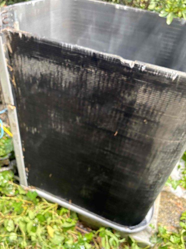 Performed thorough coil cleaning on outdoor condensing unit that exhibited heavy accumulation of dirt, debris, and organic matter on exterior mesh screening and condenser fins. The unit's heat exchange surfaces were heavily contaminated with dark buildup that significantly restricted airflow and reduced system efficiency. Cleaned and restored condenser coils to proper operating condition, removing years of accumulated outdoor contaminants to restore optimal heat transfer capability and system performance.