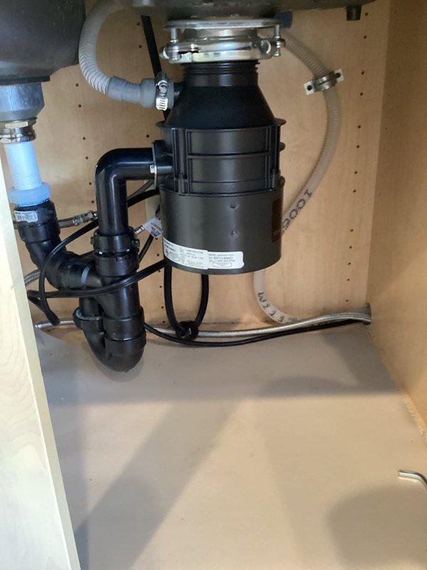Installed a new Badger 5 garbage disposal unit under the kitchen sink, including complete plumbing connections with PVC drain pipes, P-trap configuration, and electrical hookup. Verified proper operation and confirmed all connections were secure and leak-free.