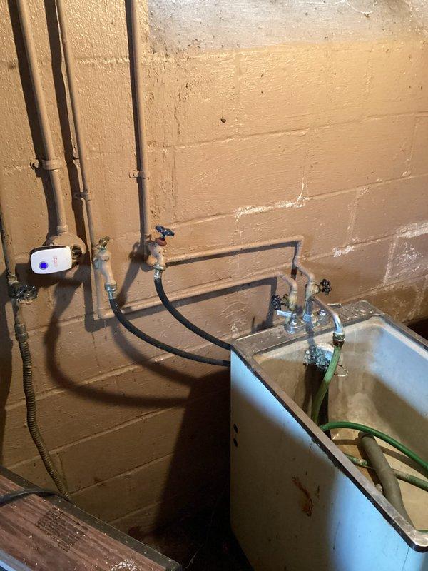 Responded to service call for multiple plumbing issues including non-functional water line behind washing machine, potential toilet replacement, and sink inspection. Upon arrival, assessed bathroom with existing toilet installation and examined utility area plumbing system. Inspected copper supply lines, shut-off valves, and water distribution system in basement mechanical room. Evaluated toilet condition and functionality, checked water supply connections, and examined bathroom sink plumbing. Documented existing conditions with photographs showing bathroom fixtures and basement utility piping configuration including flexible supply lines, mounting brackets, and valve assemblies.