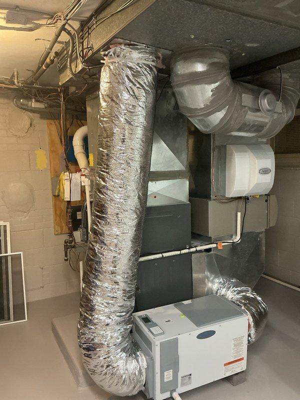 Reconfigured dehumidifier ductwork system by extending both supply and return lines to optimize performance and prevent the unit from counteracting the primary HVAC system. Installed 20 feet of 10-inch flexible ductwork with proper support using zip ties and black cloth strapping, and patched existing access holes with metal panels to restore system integrity.