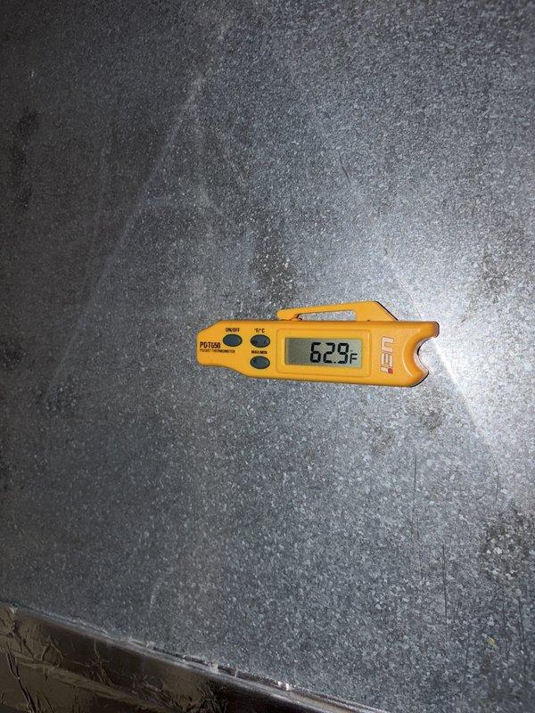 Performed routine cooling system maintenance on outdoor HVAC unit. Inspected and cleaned heavily soiled air filter that had accumulated significant dust, dirt, and debris buildup restricting airflow. Verified system temperature readings at 62.9°F using digital thermometer to confirm proper operation following maintenance completion.