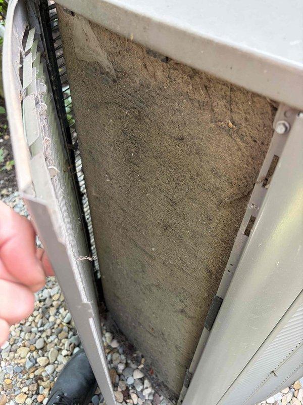Performed routine cooling system maintenance on outdoor HVAC unit. Inspected and cleaned heavily soiled air filter that had accumulated significant dust, dirt, and debris buildup restricting airflow. Verified system temperature readings at 62.9°F using digital thermometer to confirm proper operation following maintenance completion.