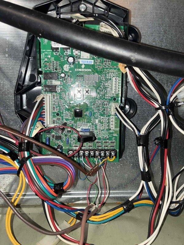 Completed scheduled cooling system maintenance visit on residential air conditioning unit. Performed comprehensive inspection of the Emerson control board assembly, verifying proper electrical connections across all terminal blocks and confirming all color-coded wiring harnesses were secure and free from damage. Measured supply air temperature at 63.3°F using calibrated digital thermometer, indicating proper cooling operation. Inspected air filtration system and verified all electronic components, capacitors, and integrated circuits on the control board were functioning within normal parameters.