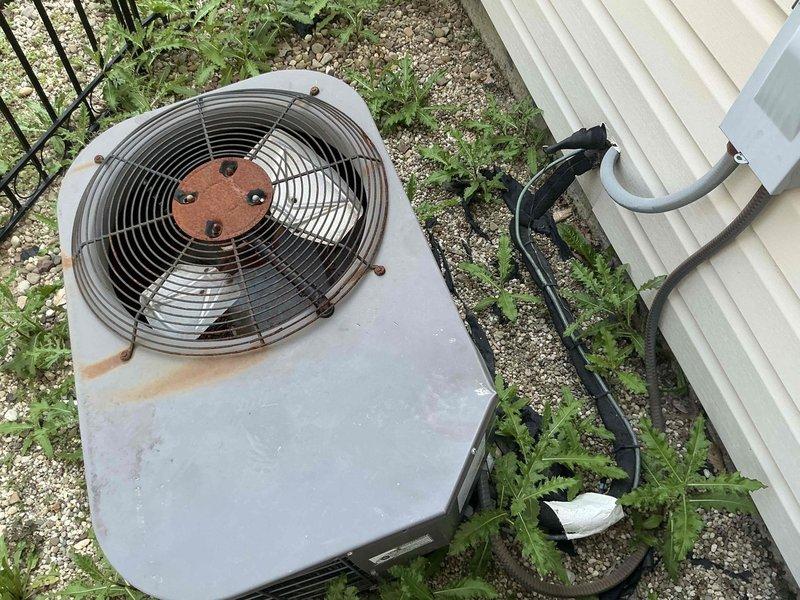 Technician responded to customer request for full HVAC system replacement options due to aging equipment. Upon arrival, conducted thorough assessment of existing outdoor condensing unit, which exhibited extensive deterioration including severe rust corrosion on fan hub assembly, mounting hardware, and cabinet surfaces. Unit showed significant weathering with rust streaking, faded paint, and overall wear consistent with extended service life beyond recommended replacement interval. Refrigerant lines and electrical conduit were inspected and documented. Site conditions noted vegetation encroachment around equipment pad and deteriorated gravel base. Comprehensive photographic documentation captured to support replacement proposal, including detailed images of corroded fan assembly, rusted cabinet components, and overall system condition. Prepared complete system replacement estimate with equipment options appropriate for customer's needs and property requirements.