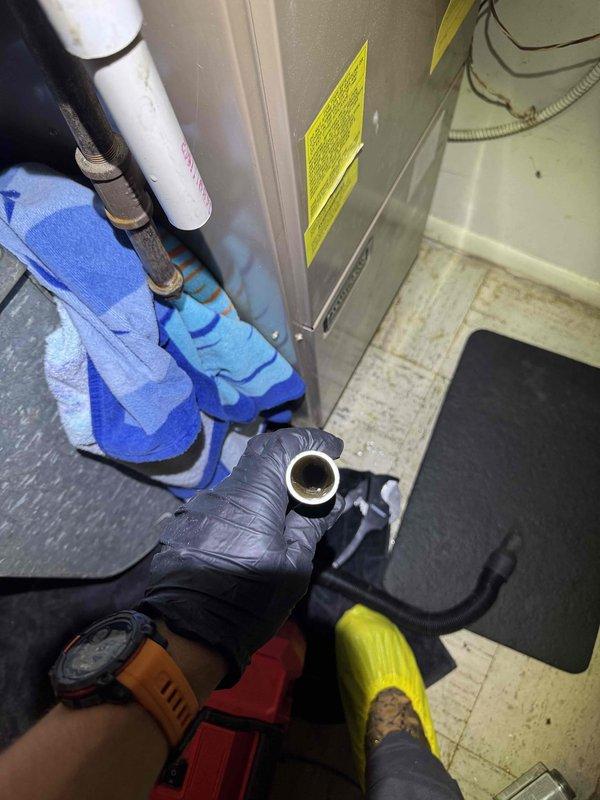 Responded to service call for clogged and leaking air conditioning system. Upon inspection, identified blockage in condensate drain line causing water backup and leakage. Cleared obstruction from drain line, replaced damaged pipe coupling, and verified proper drainage flow. Inspected both outdoor condenser units for proper operation and confirmed system returned to normal functioning without further leaks.