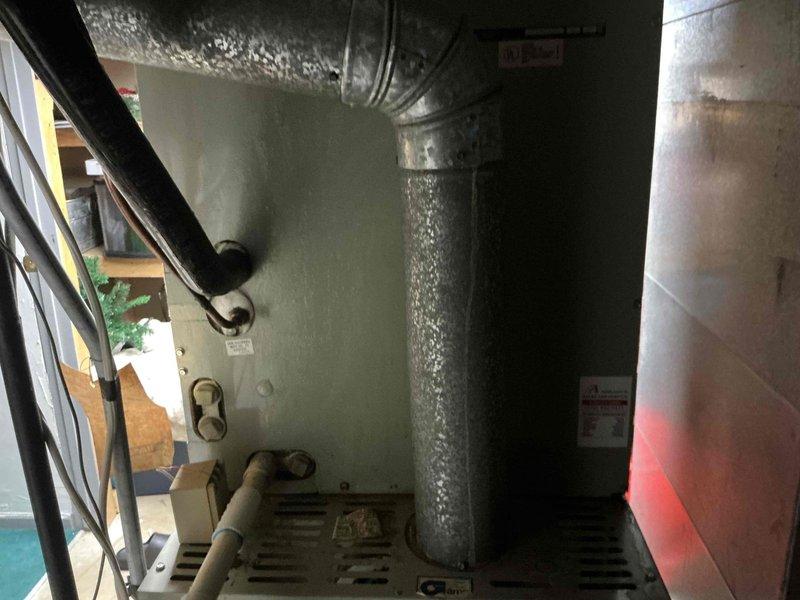 Responded to service call for 33-year-old Trane heating system with failed blower motor. Conducted comprehensive assessment of existing HVAC equipment located in basement utility area. Evaluated current system condition, noting age of equipment and operational failure. Documented installation including flexible aluminum ductwork, insulated vertical duct sections, and supporting infrastructure. Observed significant condensation on flexible ductwork indicating potential humidity issues or temperature differentials. Provided customer with detailed estimate options comparing blower motor replacement versus complete system replacement, discussing benefits and considerations of each approach given the age and condition of the existing equipment.