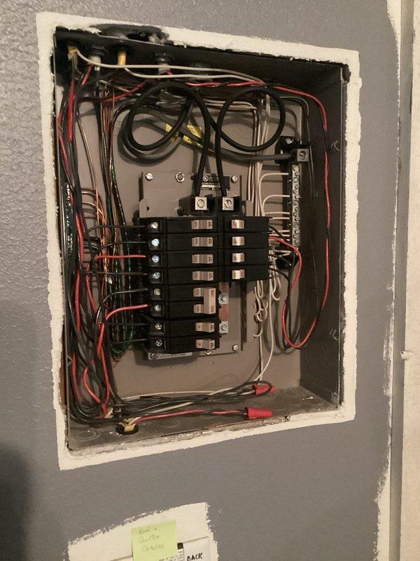Performed comprehensive electrical inspection of residential service panel and surrounding utility infrastructure. Documented existing electrical panel configuration showing dual-row circuit breaker arrangement with properly organized multi-conductor wiring in red, black, white, and yellow entering from top distribution point. Observed and photographed all breaker connections, wire routing, and termination points for code compliance verification. Extended inspection to basement mechanical room to assess electrical service proximity to plumbing infrastructure, including water heater installation and copper piping systems, ensuring adequate clearances and proper grounding paths are maintained per NEC requirements.