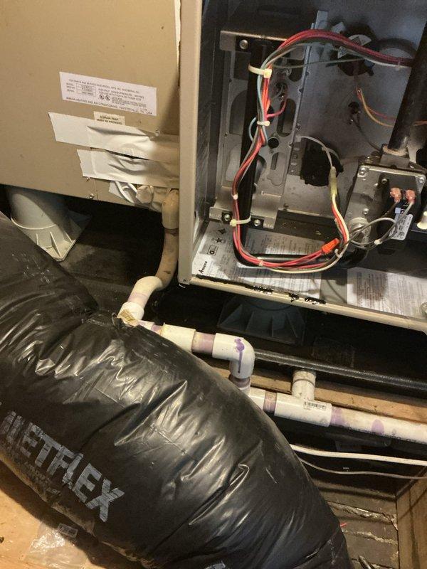 Conducted full system replacement estimate for a 23-year-old heating and cooling system located in attic of duplex property. Assessed existing gas furnace and air conditioning unit serving medium-sized residential space (1500-3000 sq.ft.) with natural gas energy source. Presented three-tiered replacement options: Good tier featuring Goodman A/C and gas furnace with up to 13.4 nominal SEER and 80% nominal AFUE; Better tier with Goodman equipment offering up to 14 nominal SEER and 96% nominal AFUE; and Best tier providing up to 16 nominal SEER and 96% nominal AFUE efficiency ratings. Documented existing system conditions including attic-mounted unit with accessible internal components, exposed electrical wiring, circuit boards, and mechanical assemblies. Noted black flexible ductwork with silver metallic insulation throughout attic space, PVC condensate drainage piping, and visible dust accumulation on aging components. Photographed current installation showing open access panel revealin