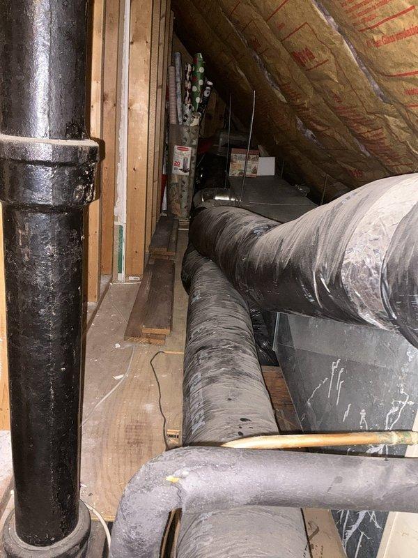 Conducted full system replacement estimate for a 23-year-old heating and cooling system located in attic of duplex property. Assessed existing gas furnace and air conditioning unit serving medium-sized residential space (1500-3000 sq.ft.) with natural gas energy source. Presented three-tiered replacement options: Good tier featuring Goodman A/C and gas furnace with up to 13.4 nominal SEER and 80% nominal AFUE; Better tier with Goodman equipment offering up to 14 nominal SEER and 96% nominal AFUE; and Best tier providing up to 16 nominal SEER and 96% nominal AFUE efficiency ratings. Documented existing system conditions including attic-mounted unit with accessible internal components, exposed electrical wiring, circuit boards, and mechanical assemblies. Noted black flexible ductwork with silver metallic insulation throughout attic space, PVC condensate drainage piping, and visible dust accumulation on aging components. Photographed current installation showing open access panel revealin