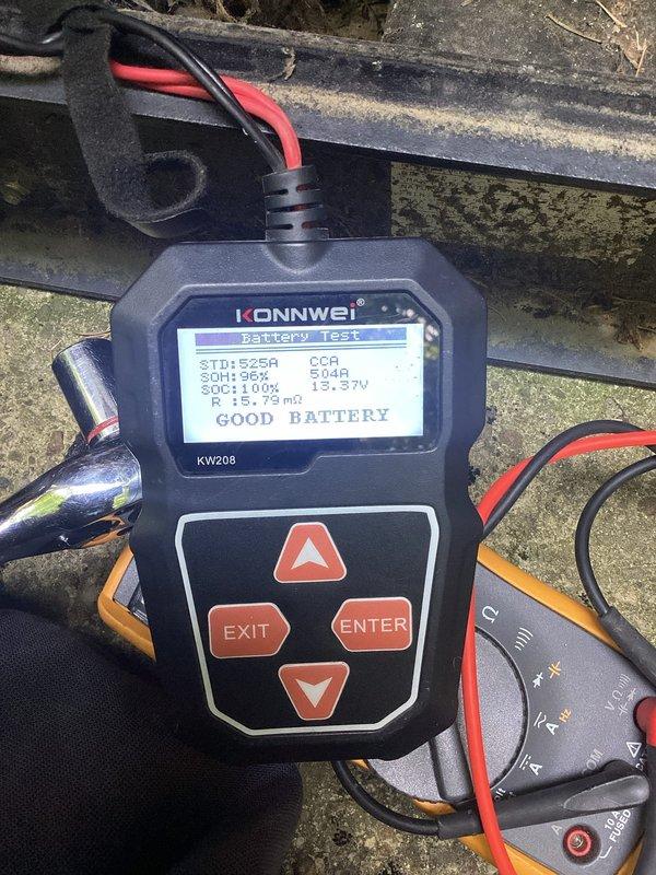 Responded to service call for generator displaying solid blue indicator light with reported starting issues. Customer had previously replaced batteries and starter assembly without resolution and suspected fuel delivery system malfunction. Performed comprehensive electrical system diagnostics using battery load tester, which confirmed battery in good condition with 12.59V reading, 504A CCA, 96% state of health, and 100% state of charge. Conducted additional measurements using digital multimeter to verify electrical connections and system integrity. Documented equipment condition and diagnostic results with photographs for service records. Based on testing results, electrical components and battery system are functioning within normal parameters, suggesting issue may be related to fuel delivery system as customer suspected, which would require further investigation of gas line, fuel filter, and carburetor components.