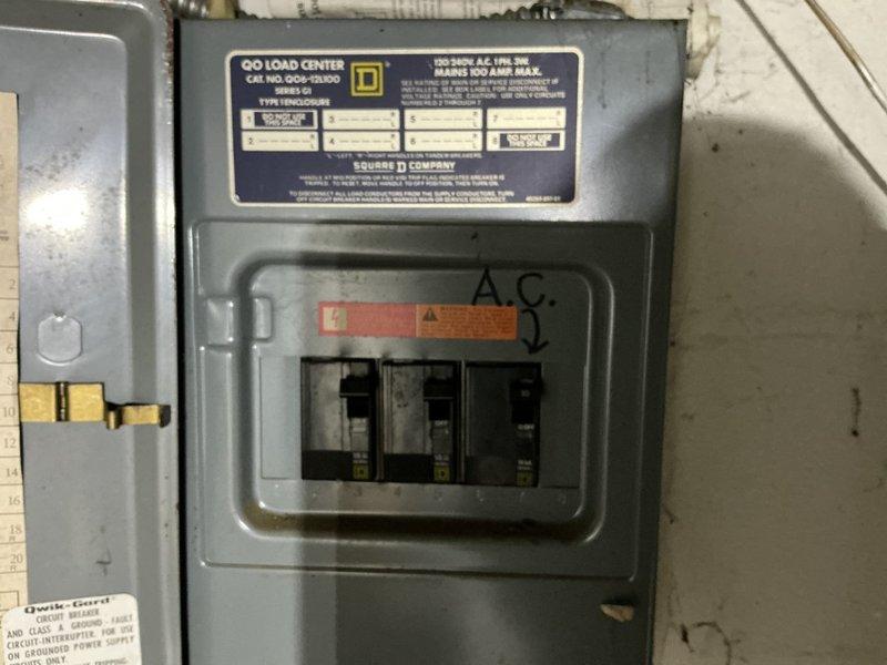 Conducted comprehensive assessment of existing R22 residential HVAC system to provide full system replacement options. Evaluated current air conditioning unit, electrical panel configuration with dedicated A.C. circuit breaker, and outdoor condenser unit placement near foundation. Documented existing equipment specifications and electrical infrastructure to develop replacement proposals addressing obsolete R22 refrigerant system. Photographed electrical subpanel showing circuit breaker setup and exterior unit location adjacent to glass block basement windows for accurate equipment sizing and installation planning.
