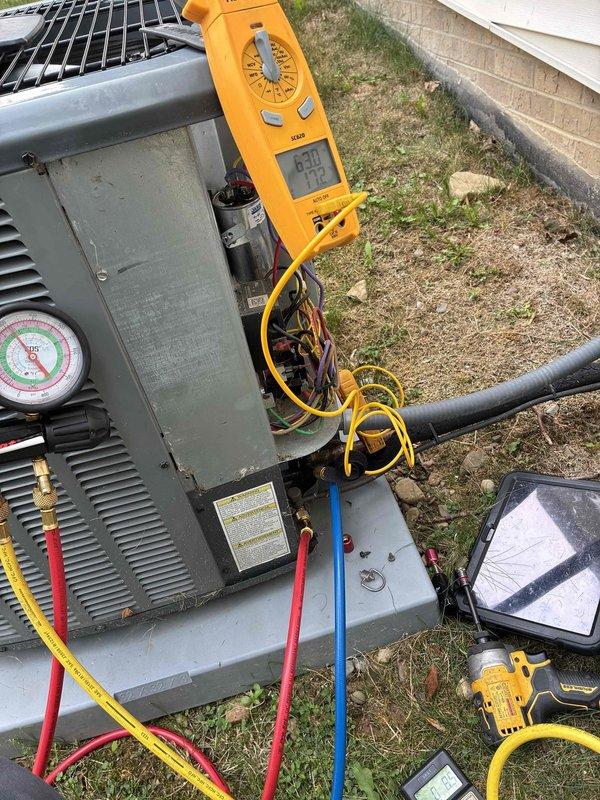 # HVAC Service Call - No Cooling Issue

Responded to service call for air conditioning unit running but not producing cool air. Upon arrival, performed diagnostic testing on outdoor condensing unit. Removed access panel to inspect internal electrical components and wiring connections.

Used digital multimeter to test capacitor functionality, recording measurements of 99.0 and 29.9 MFD. Connected manifold gauge set with refrigerant hoses to service ports to check system pressures and diagnose cooling failure. Tested electrical connections and voltage readings at compressor and fan motor terminals using clamp meter.

Based on diagnostic findings from capacitor testing and system pressure readings, identified root cause of no cooling condition. Completed necessary repairs to restore system operation and proper cooling performance. Verified all electrical connections secure and system operating within normal parameters before closing access panel and completing service call.