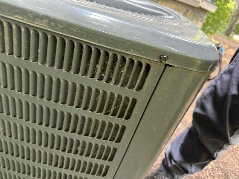 Performed comprehensive cooling season tune-up on residential air conditioning system. Conducted electrical measurements using digital clamp meter, recording temperature readings at condenser unit which showed 45.7°C. Inspected outdoor condenser unit with green metal housing, noting dust and debris accumulation on coil fins requiring attention during routine maintenance service.