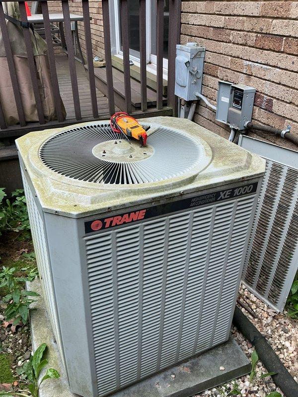 # Mini Split System Diagnostic and Repair

Responded to service call for non-operational mini split cooling system. Property has two mini split units aged 9 and 11 years respectively. Upon arrival, performed comprehensive diagnostic testing on both outdoor condensing units and indoor air handlers.

Utilized digital multimeter to test electrical components on the Trane XE 1000 outdoor unit. Measured voltage and amperage at compressor, contactor, and capacitor to identify potential electrical failures. Noted significant weathering and debris accumulation on outdoor unit surfaces, including biological growth on top panel which can impede heat transfer efficiency.

Inspected refrigerant line sets connecting outdoor units to indoor air handlers. Verified integrity of insulation on copper refrigerant lines running through basement utility area. Checked for refrigerant leaks using appropriate detection methods at all connection points and service valves.

Evaluated indoor furnace and air hand