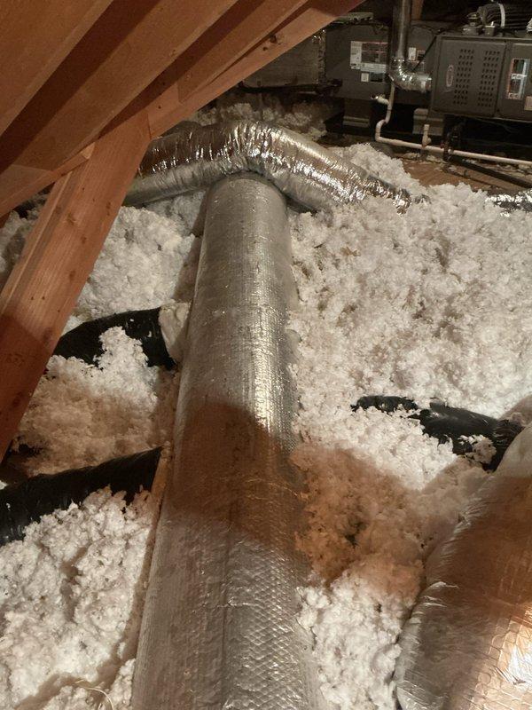 Responded to no cooling complaint and performed system inspection. Accessed attic-mounted HVAC equipment and inspected ductwork installation, insulation coverage, and air distribution components. Verified proper duct connections and documented existing system configuration with flexible ductwork running through insulated attic space.