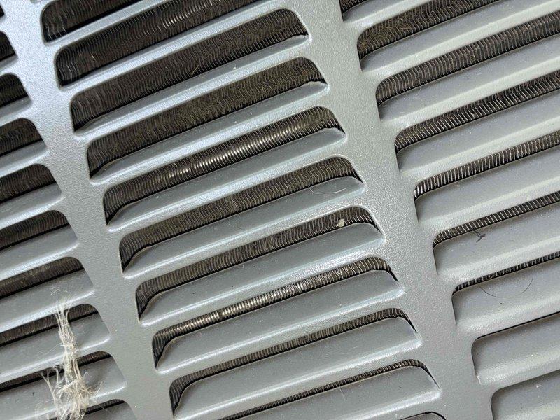 Completed scheduled cooling system maintenance on residential HVAC unit. Inspected and tested electrical components including dual Edison ECNR 30 amp fuses, which showed minor discoloration and burn marks at connection points but remained within operational parameters. Examined evaporator coil fins and heat exchanger assembly, noting oxidation and age-related discoloration on copper/aluminum fins while confirming adequate airflow through densely packed fin arrangement. All critical components operational and system returned to service.