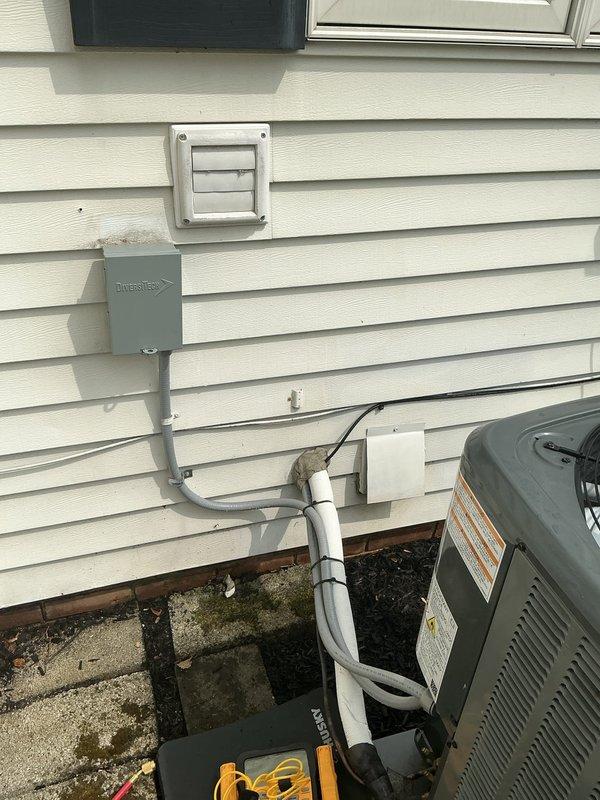 Responded to service call for AC and furnace running continuously with insufficient cooling, unable to reach setpoint of 72° and maintaining 78° throughout residence. Systems were recently installed approximately six months prior. Arrived on-site midday and performed diagnostic evaluation of both heating and cooling equipment. Inspected outdoor condensing unit with A2L refrigerant system, verified refrigerant line connections and insulation integrity along exterior wall penetrations. Checked electrical connections at outdoor disconnect and conduit terminations. Documented equipment installation with exterior unit positioning on decorative rock base and proper line set routing with appropriate support strapping. Systems appeared to be recently commissioned based on condition and labeling compliance for new A2L refrigerant safety requirements.