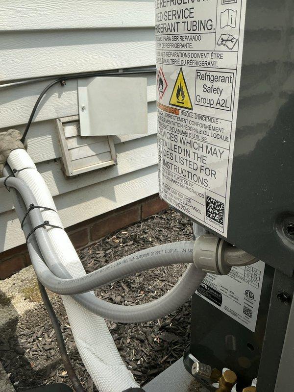 Responded to service call for AC and furnace running continuously with insufficient cooling, unable to reach setpoint of 72° and maintaining 78° throughout residence. Systems were recently installed approximately six months prior. Arrived on-site midday and performed diagnostic evaluation of both heating and cooling equipment. Inspected outdoor condensing unit with A2L refrigerant system, verified refrigerant line connections and insulation integrity along exterior wall penetrations. Checked electrical connections at outdoor disconnect and conduit terminations. Documented equipment installation with exterior unit positioning on decorative rock base and proper line set routing with appropriate support strapping. Systems appeared to be recently commissioned based on condition and labeling compliance for new A2L refrigerant safety requirements.