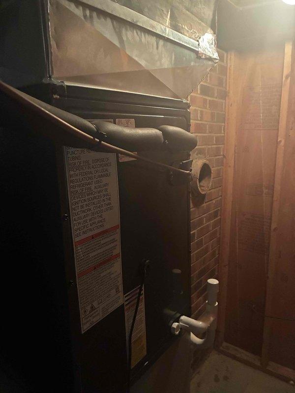 Completed installation of new air conditioning system in basement utility area. Unit was properly positioned against existing brick wall with connection to overhead ductwork and air handler. System was charged with refrigerant and tested using digital manifold gauges, confirming proper operating pressures of 139.6 psi low side and 275.4 psi high side, with superheat and subcooling measurements within manufacturer specifications at ambient conditions.