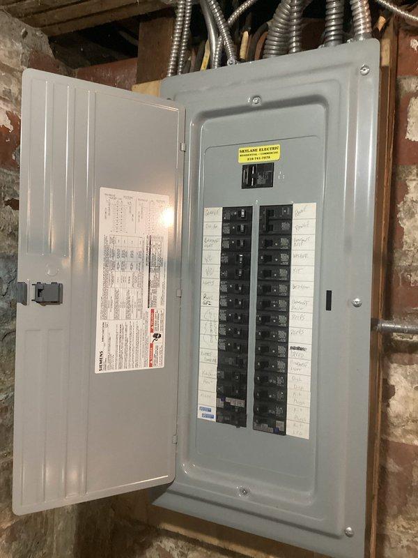 Conducted comprehensive electrical estimate for fixture replacement and potential rewiring project at 90-year-old residential property. Assessed exterior light fixtures at back door location requiring replacement, with customer-supplied parts available for installation. Documented existing electrical infrastructure including aged circuit breaker panel with handwritten circuit labels and multiple conduit entries, identifying need for consultation regarding partial home rewiring due to age of electrical system. Photographed current conditions of electrical panel mounted in unfinished basement area and interior lighting fixtures to support estimate preparation and future scope of work planning.