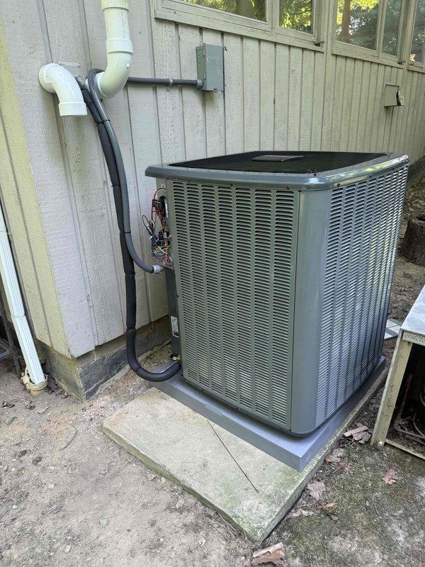 Completed full HVAC system installation including a new 96% high-efficiency gas furnace and matching air conditioning condenser unit. The furnace was installed with all internal components properly wired and connected, including blower motor assembly, heat exchanger with burner ports, gas valve with brass fittings, electrical relays, and control wiring. The outdoor condenser unit was positioned on a protective pad over a concrete slab foundation with proper clearance from the structure, connected via insulated refrigerant lines and electrical disconnect, with PVC condensate drain routed vertically along the exterior wall.