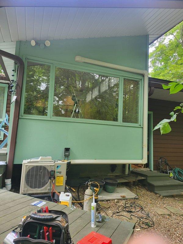 Completed installation of Daikin ductless mini-split system at residential property. Mounted outdoor condenser unit on wooden deck and installed indoor wall-mounted air handler above window in living space, running refrigerant lines and electrical connections between units. System tested and confirmed operational upon completion.