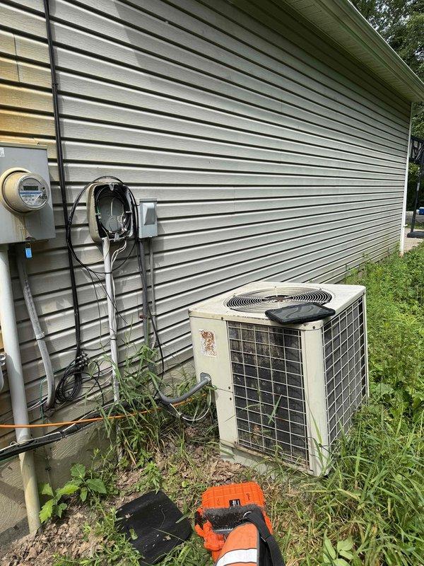 Responded to no cooling complaint on residential split system air conditioning unit. Upon arrival, performed visual inspection of outdoor condensing unit showing significant weathering and age-related deterioration with rust staining on exterior panels. Unit located on exterior wall with overgrown vegetation requiring clearance attention. Inspected indoor air handler and furnace equipment in basement mechanical room. Evaluated electrical connections at outdoor disconnect and service panel. Assessed refrigerant lines, ductwork connections, and overall system operation. Documented equipment condition with photos showing 10+ year old system with visible wear patterns consistent with age and exposure. Collected diagnostic fee as requested.