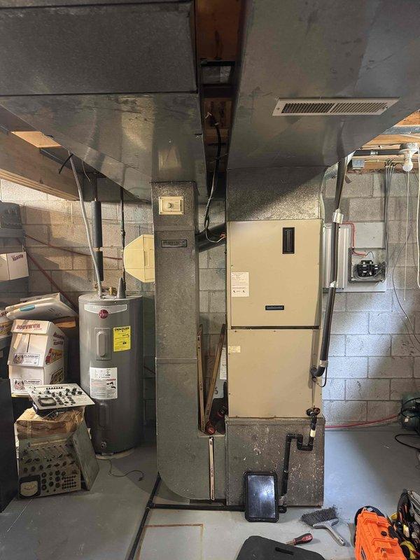 Responded to no cooling complaint on residential split system air conditioning unit. Upon arrival, performed visual inspection of outdoor condensing unit showing significant weathering and age-related deterioration with rust staining on exterior panels. Unit located on exterior wall with overgrown vegetation requiring clearance attention. Inspected indoor air handler and furnace equipment in basement mechanical room. Evaluated electrical connections at outdoor disconnect and service panel. Assessed refrigerant lines, ductwork connections, and overall system operation. Documented equipment condition with photos showing 10+ year old system with visible wear patterns consistent with age and exposure. Collected diagnostic fee as requested.