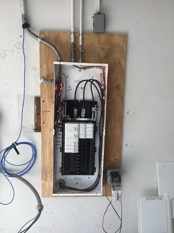 Completed 100 amp electrical service upgrade with new main panel installation mounted on wooden backing board. Installed new circuit breaker configuration with dual rows of breakers and proper wire management for all branch circuits. Replaced two GFCI receptacles to ensure ground fault protection compliance. All work performed to current electrical code standards with proper conduit routing and secure panel mounting.