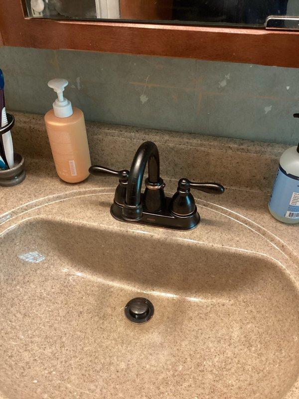 Completed installation of new lavatory faucet with oil-rubbed bronze finish and dual lever handles on existing countertop. Replaced tub trim kit, installed new standpipe assembly with white PVC drain configuration including multiple joints and connections, and replaced main water shut-off valve. All supply lines and drain connections tested and verified leak-free upon completion.