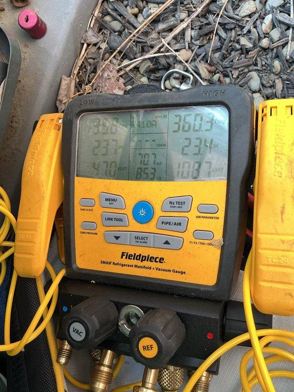 Responded to air conditioning water leak complaint. Upon arrival, inspected HVAC system and accessed unit housed in green metal cabinet enclosure. Connected Fieldpiece SMAN refrigerant manifold gauge to system and performed diagnostic testing of refrigerant pressures and temperatures to rule out low refrigerant charge as cause of leak. Readings indicated system pressures within normal operating parameters, confirming leak was condensate-related rather than refrigerant issue.