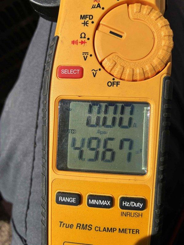 Completed comprehensive cooling system tune-up including inspection of evaporator coil assembly and refrigerant lines where condensation buildup was observed on internal components. Verified system amperage draw at 0.000A and measured voltage at 496.7V AC using clamp meter to confirm proper electrical operation and system performance.