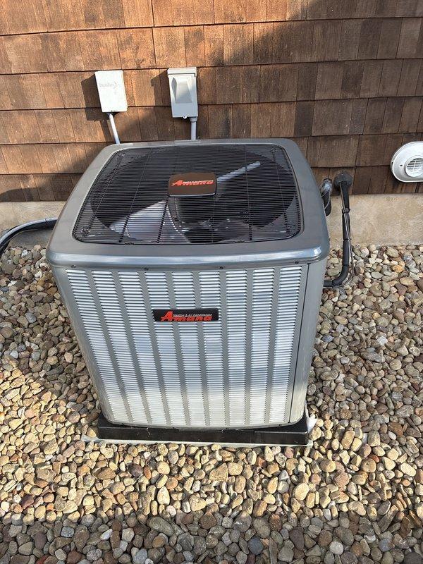 Completed installation of Amana air conditioning system including outdoor condenser unit and air handler. Unit was properly mounted on rubber isolation pad over landscaping stone base, with all electrical connections terminated to wall-mounted disconnect and conduit runs completed per code. System was charged to manufacturer specifications at 400 oz refrigerant weight, tested for proper operation, and left in full working condition.