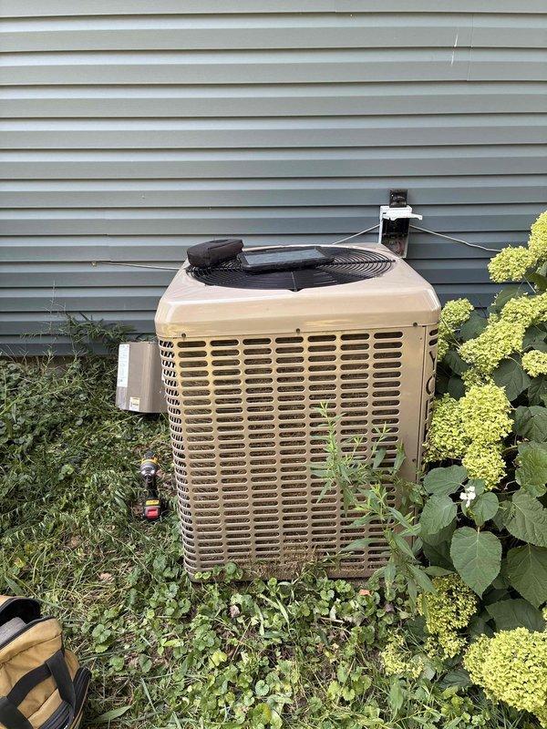 Completed comprehensive cooling system tune-up on residential air conditioning unit. Inspected and serviced outdoor condenser unit, noting significant vegetation overgrowth requiring clearance recommendation for optimal airflow and efficiency. Examined electrical components including capacitor, wiring connections, and control circuits; all connections found secure despite visible dust accumulation within cabinet, which was addressed during maintenance procedures.