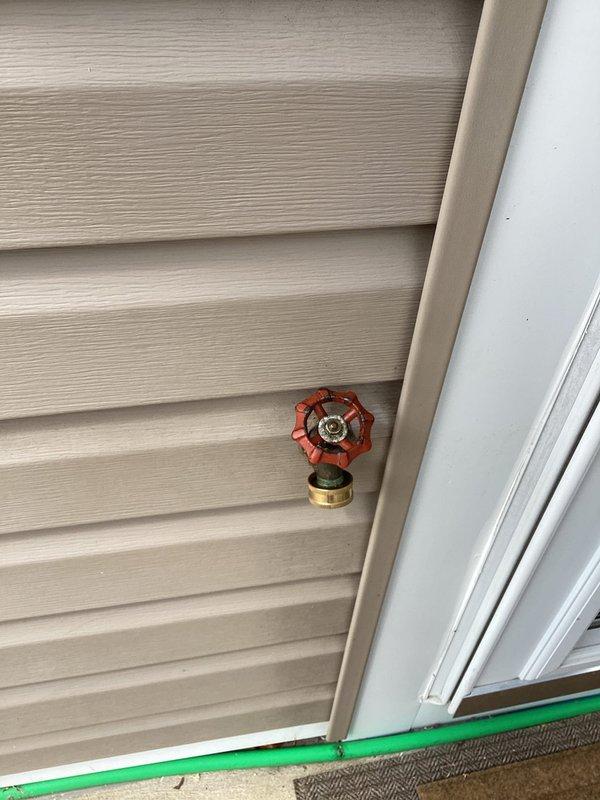 Responded to service call for outdoor water spigot with malfunctioning valve handle that continuously turned without engaging the shutoff mechanism. Inspected exterior hose bib mounted on vinyl siding and determined the valve stem had stripped internal threads, preventing proper operation of the red wheel-style handle. Replaced defective outdoor spigot assembly with new frost-proof hose bib, ensuring proper mounting to exterior wall and secure connection to supply line.