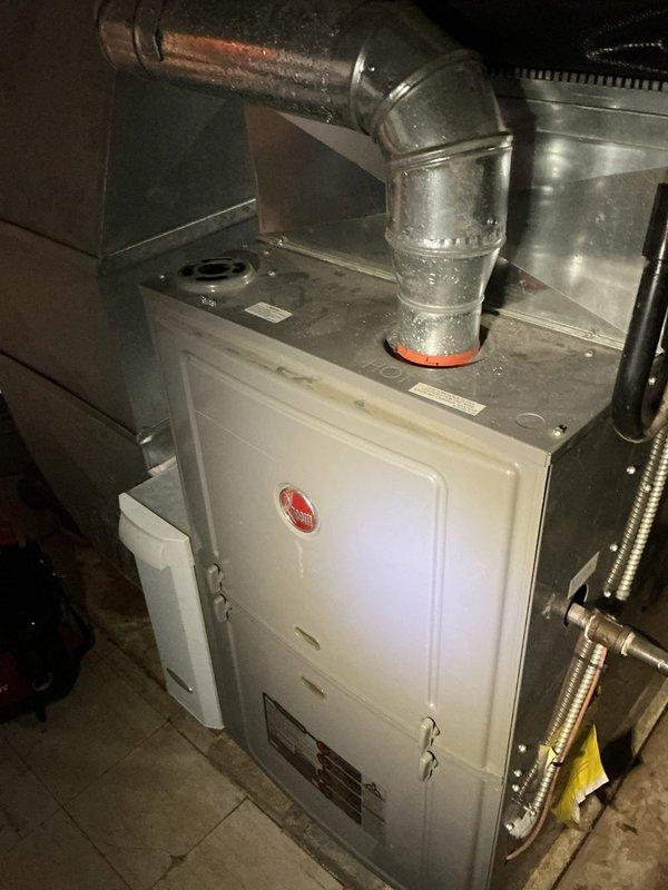 Responded to service call for non-operational air conditioning system on 15-year-old residential unit. Upon arrival, performed diagnostic evaluation of complete HVAC system including furnace/air handler assembly and outdoor condensing unit. Conducted visual inspection of indoor equipment, verifying electrical connections, control panel functionality, and ductwork integrity. Examined refrigerant line insulation, condensate drainage components, and furnace blower assembly for proper operation. Documented equipment condition through photographic records showing air handler installation, ductwork connections, and associated mechanical components in utility space. System evaluation completed to determine cause of cooling failure and provide recommendations for repair or replacement options based on age and condition of existing equipment.