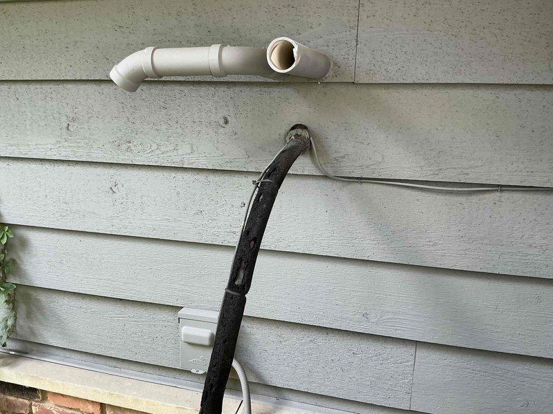 Conducted comprehensive site evaluation for Bryant air conditioning system replacement at residential property. Documented existing outdoor condensing unit location in courtyard area adjacent to building entrance, assessed utility line routing including refrigerant lines and electrical connections along exterior siding, and photographed current installation configuration to develop equipment replacement options for customer consideration.