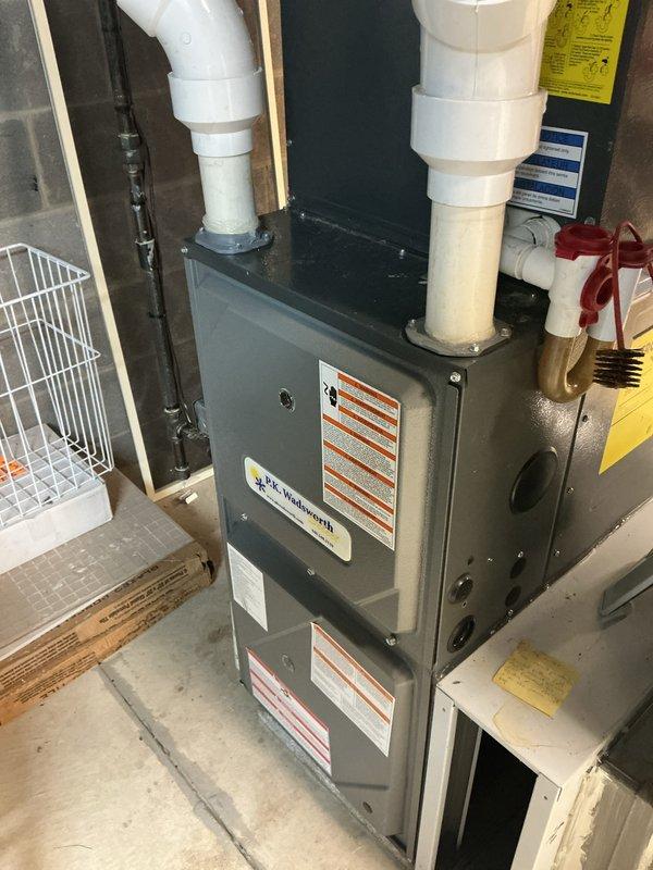 Completed scheduled cooling system maintenance on residential HVAC unit. Inspected furnace cabinet, verified proper venting through PVC intake and exhaust pipes, examined pleated air filter for cleanliness and airflow efficiency, and documented equipment condition with warning labels intact and visible. All components operating within normal parameters with no issues identified during this preventive maintenance visit.