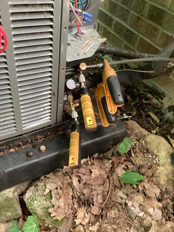 Completed routine cooling maintenance on outdoor HVAC unit, including refrigerant line inspection and electrical diagnostics using digital multimeter on ductwork connections. All system components tested and found operating within normal parameters, with tools staged for refrigerant pressure checks and connection service.
