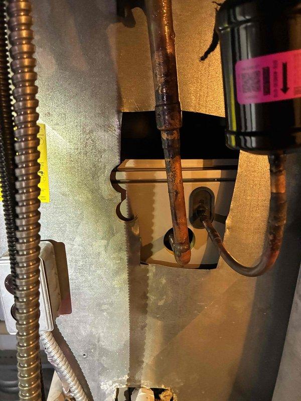 Responded to service call for air conditioning system experiencing progressive water leakage. Upon inspection, identified severely corroded copper refrigerant lines within the air handler cabinet, exhibiting extensive rust and oxidation damage with compromised pipe integrity. The deterioration showed evidence of prolonged moisture exposure and active corrosion at connection points to the control box assembly. Documented existing conditions with photographic evidence showing the extent of copper pipe degradation and associated water damage in the mechanical area.