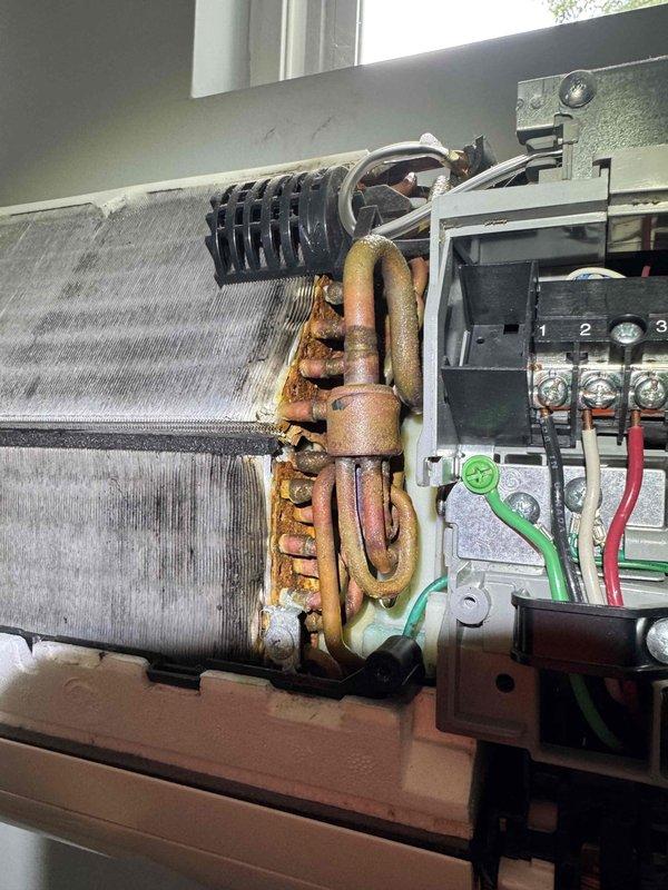Responded to no cooling complaint on mini-split system. Upon inspection, discovered heavily corroded copper U-bend piping at evaporator coil assembly with significant rust deterioration, and found substantial dirt and debris accumulation on air filter and internal components. Documented equipment condition showing advanced oxidation on refrigerant lines and compromised filtration system requiring immediate attention to restore proper cooling operation.