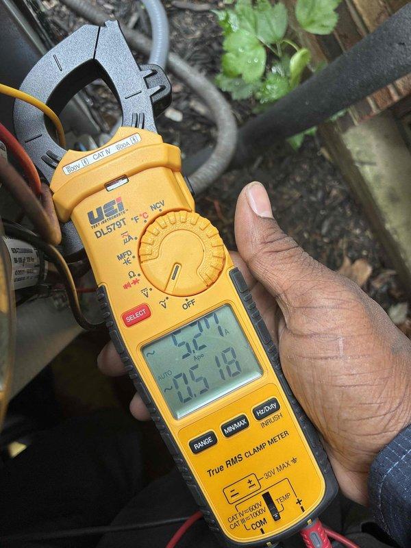 Completed routine cooling system maintenance on aging HVAC unit as part of ongoing preventive service program. Inspected heat exchanger coil assembly, noting accumulated dust and debris between fins which is typical for systems of this age. Measured electrical parameters using clamp meter, recording voltage reading of 305.182V to verify proper system operation and power supply stability. Unit confirmed operational and functioning within acceptable parameters following maintenance procedures.
