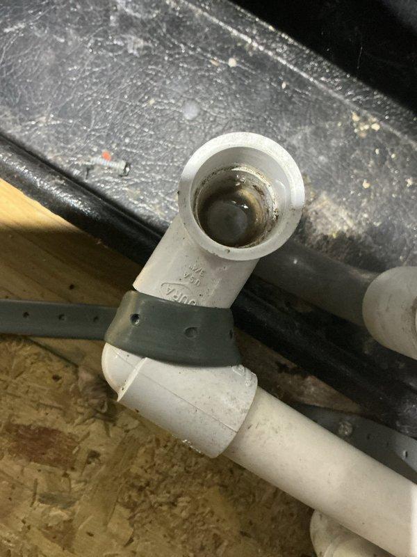 Responded to report of water leak originating from attic-mounted air conditioning unit causing ceiling damage. Upon inspection, identified condensate drainage issue at PVC drain line connection point with improper pitch or blockage causing water overflow. Condensate leak had saturated ceiling material, requiring removal of damaged drywall section to expose structural joists and allow proper drying. Cleared condensate drain line obstruction, verified proper drainage flow, and secured drain line connections with appropriate clamps. Confirmed unit is now draining properly with no active leaks present.