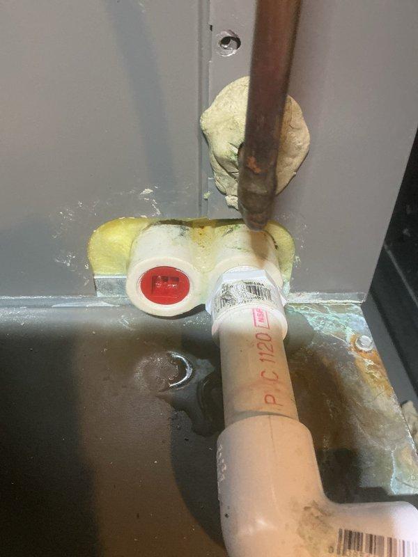 Responded to callback for reported AC refrigerant leak that had previously been investigated without successful recreation. Performed thorough inspection of system including refrigerant lines, connections, and penetration points. Documented copper line penetration through wall with spray foam seal and associated PVC drainage system connections. Inspected water heater area plumbing connections and pressure relief valve assembly for potential condensate leak sources that may have been mistaken for refrigerant leak. Unable to locate active leak at time of service call.