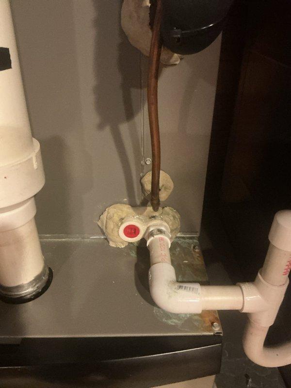 Responded to callback for reported AC refrigerant leak that had previously been investigated without successful recreation. Performed thorough inspection of system including refrigerant lines, connections, and penetration points. Documented copper line penetration through wall with spray foam seal and associated PVC drainage system connections. Inspected water heater area plumbing connections and pressure relief valve assembly for potential condensate leak sources that may have been mistaken for refrigerant leak. Unable to locate active leak at time of service call.