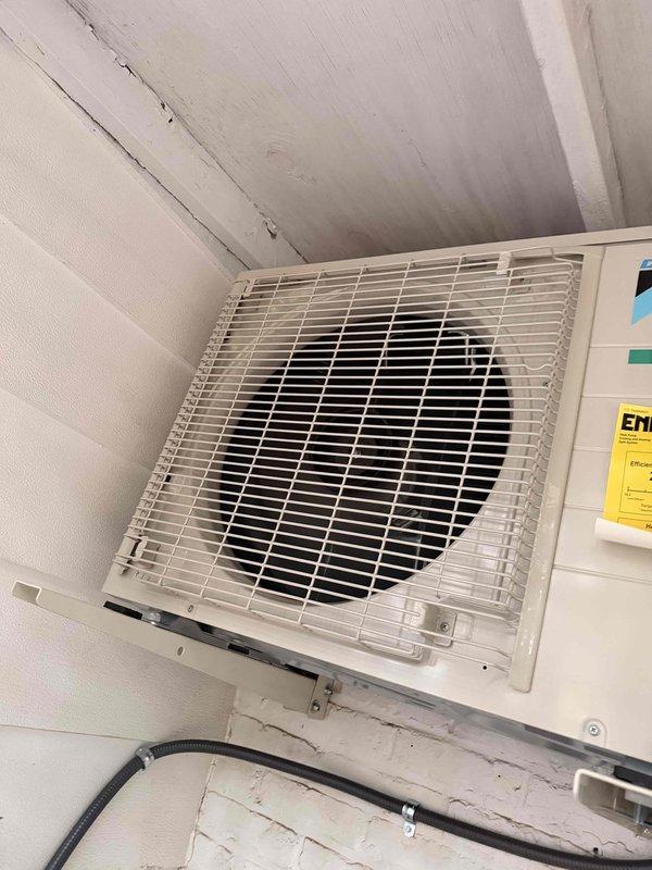 Completed installation of single-head ductless mini-split system, including outdoor condensing unit mounted on exterior wall with proper drainage line routing and indoor wall-mounted air handler positioned near ceiling for optimal air distribution. System tested and verified operational with all components functioning correctly.