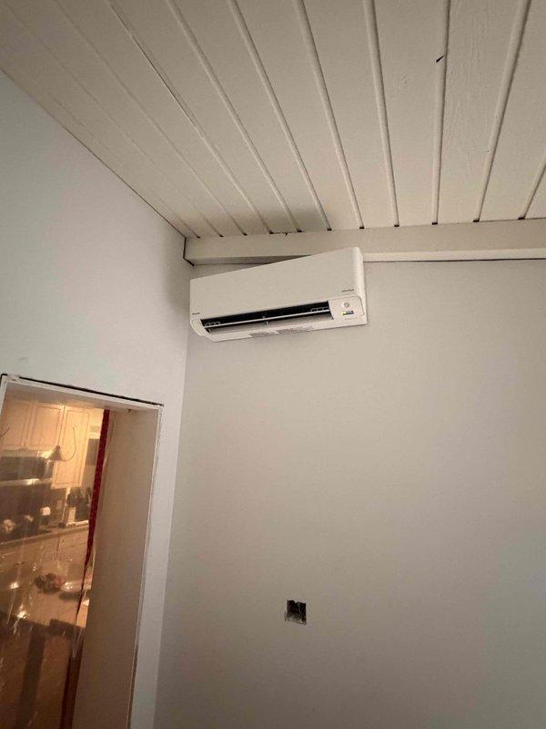 Completed installation of single-head ductless mini-split system, including outdoor condensing unit mounted on exterior wall with proper drainage line routing and indoor wall-mounted air handler positioned near ceiling for optimal air distribution. System tested and verified operational with all components functioning correctly.
